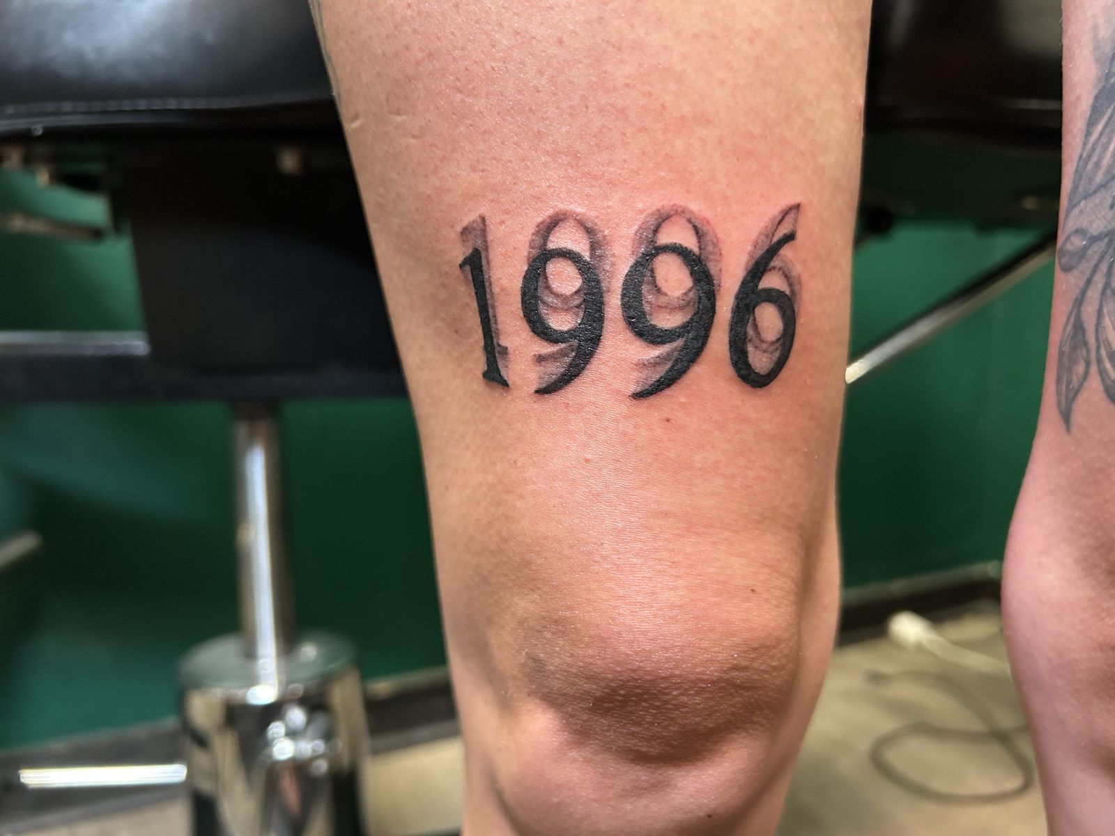 1996 shadow lettering tattoo above the knee